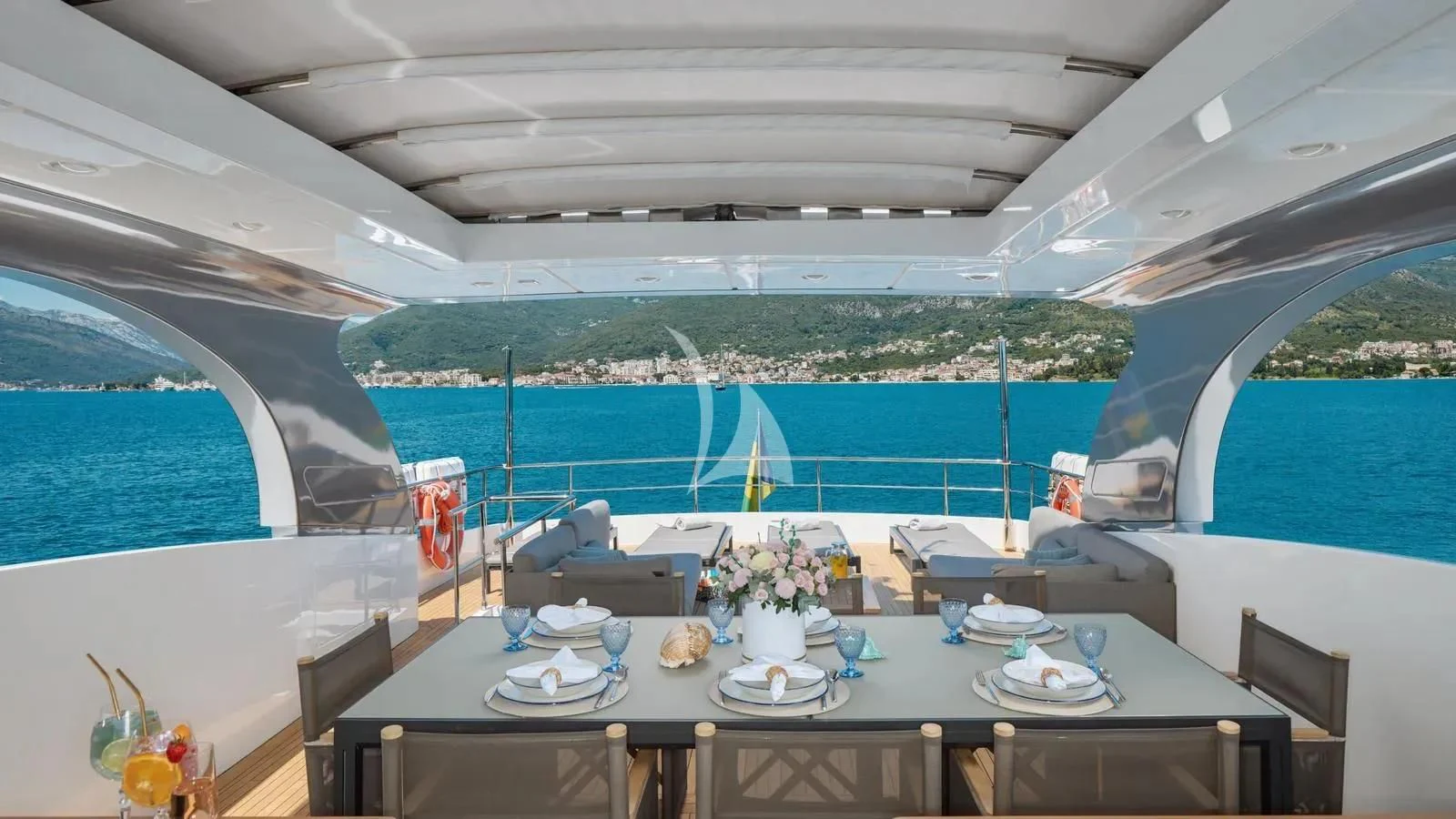 a table with plates and cups on it next to a body of water aboard PERTULA Yacht for Sale