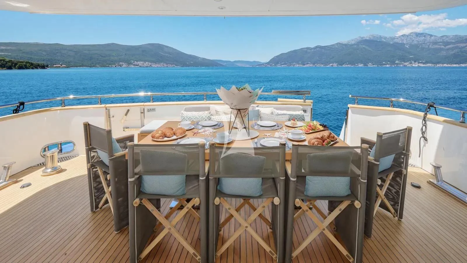 a table set for a meal on a deck overlooking the ocean aboard PERTULA Yacht for Sale