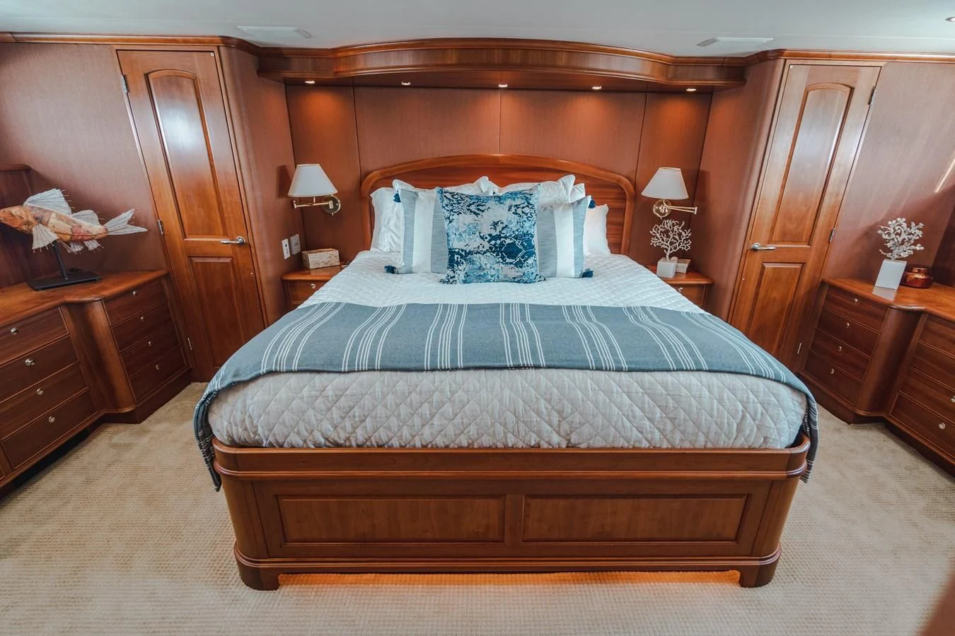 a bed with a blue and white comforter and a wooden headboard aboard L'DOR V'DOR Yacht for Sale