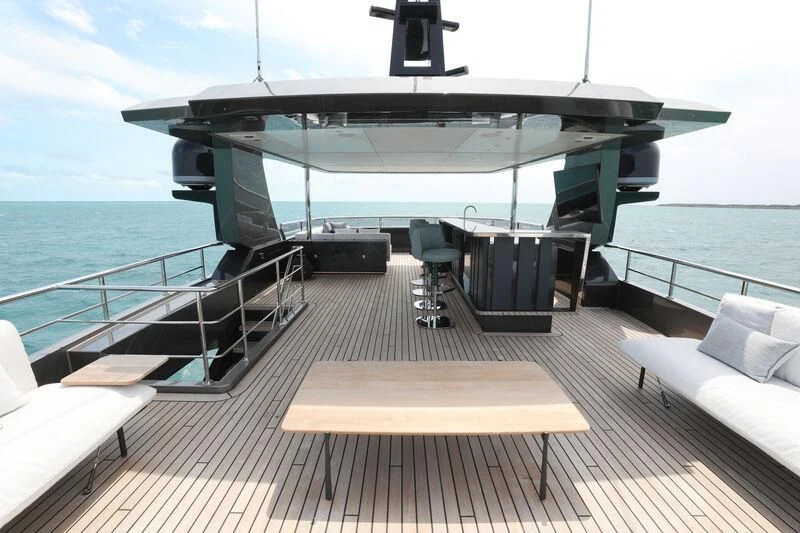 a deck with a table and chairs on it by the water aboard A SALT WEAPON Yacht for Charter