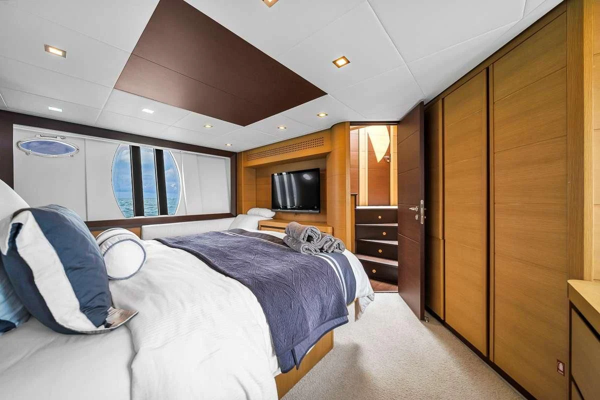 a room with a bed and a television aboard VANTAGE Yacht for Charter