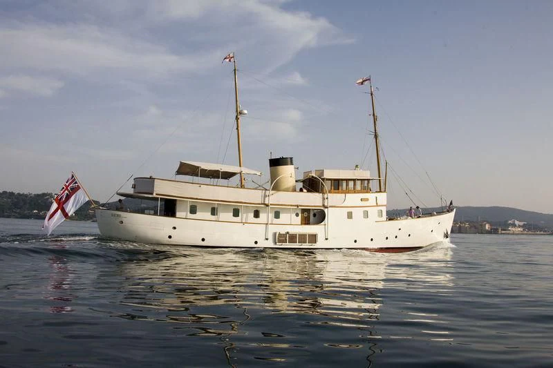 a large white boat with a flag on it aboard BLUE BIRD OF 1938 Yacht for Sale