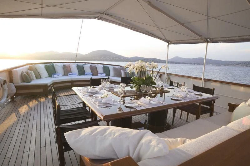a table with chairs and a view of the ocean aboard BLUE BIRD OF 1938 Yacht for Sale