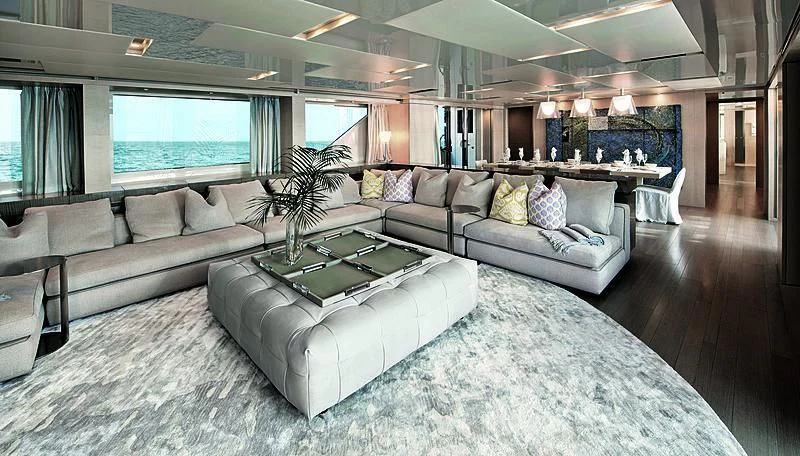 a large living room with a large gray couch and a large window aboard RUSCELLO Yacht for Sale