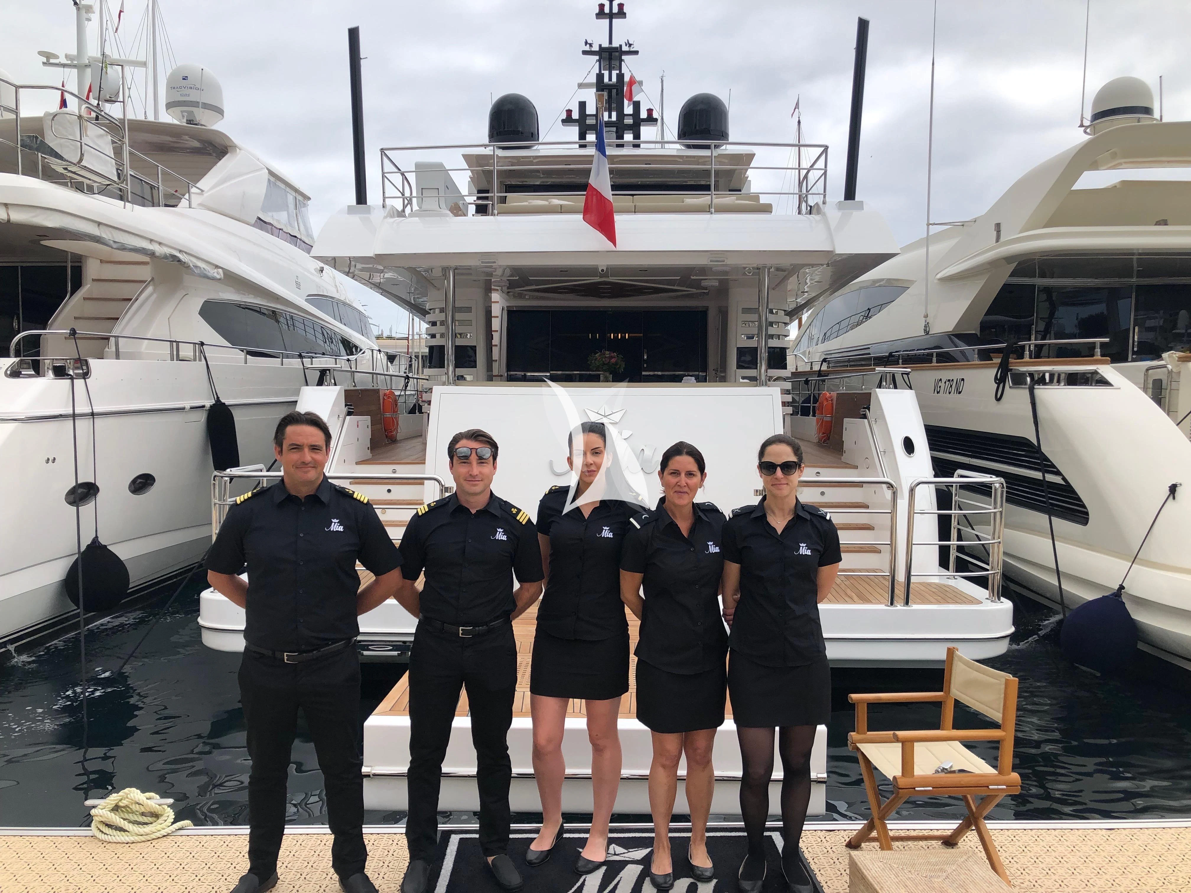 a group of people posing for a photo in front of a docked boat aboard LEGACY Yacht for Sale