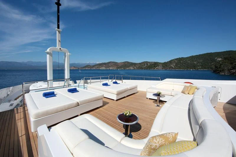 a room with a bed and a table with a chair and a white bed on a boat in aboard VICA Yacht for Sale