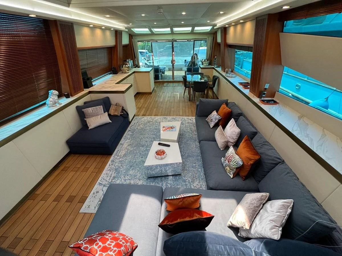 a living room with a large blue couch and a large window aboard EYE Yacht for Sale