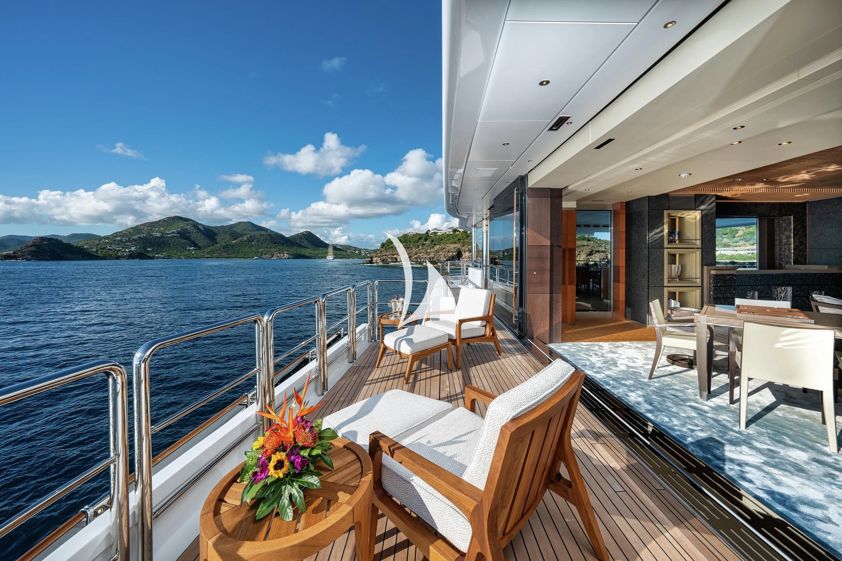 a deck with tables and chairs on it and a body of water in the background aboard BARBARA Yacht for Charter