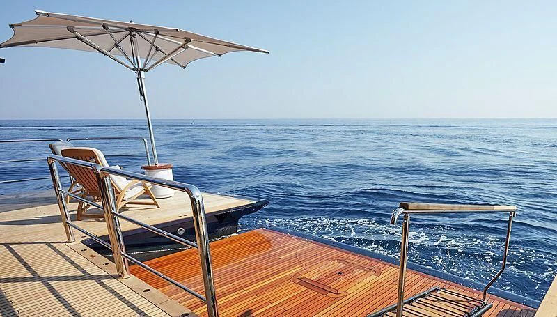 a chair and umbrella on a deck by the water aboard BARBARA Yacht for Charter