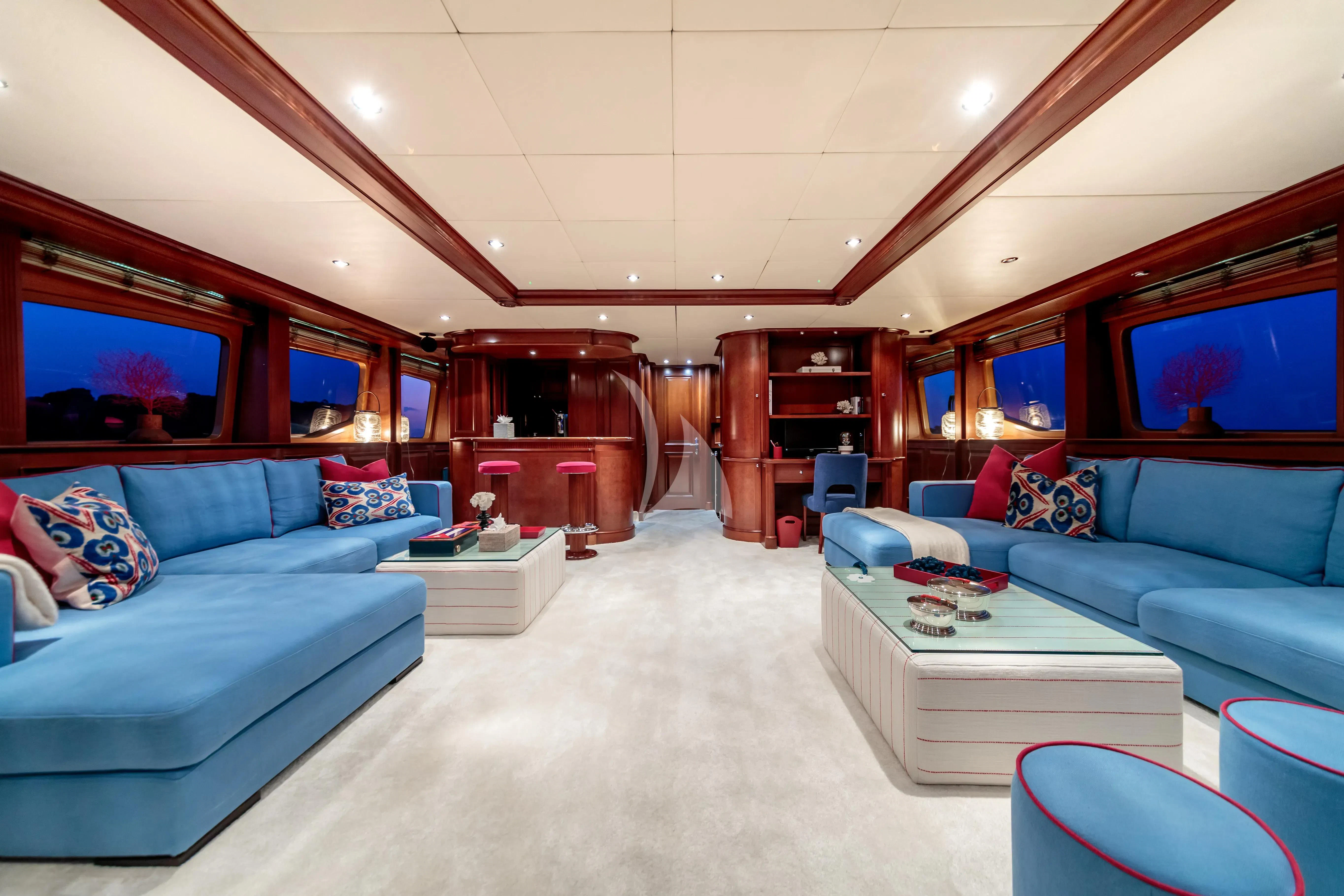 a living room with a blue couch and a large mirror aboard BANG! Yacht for Charter
