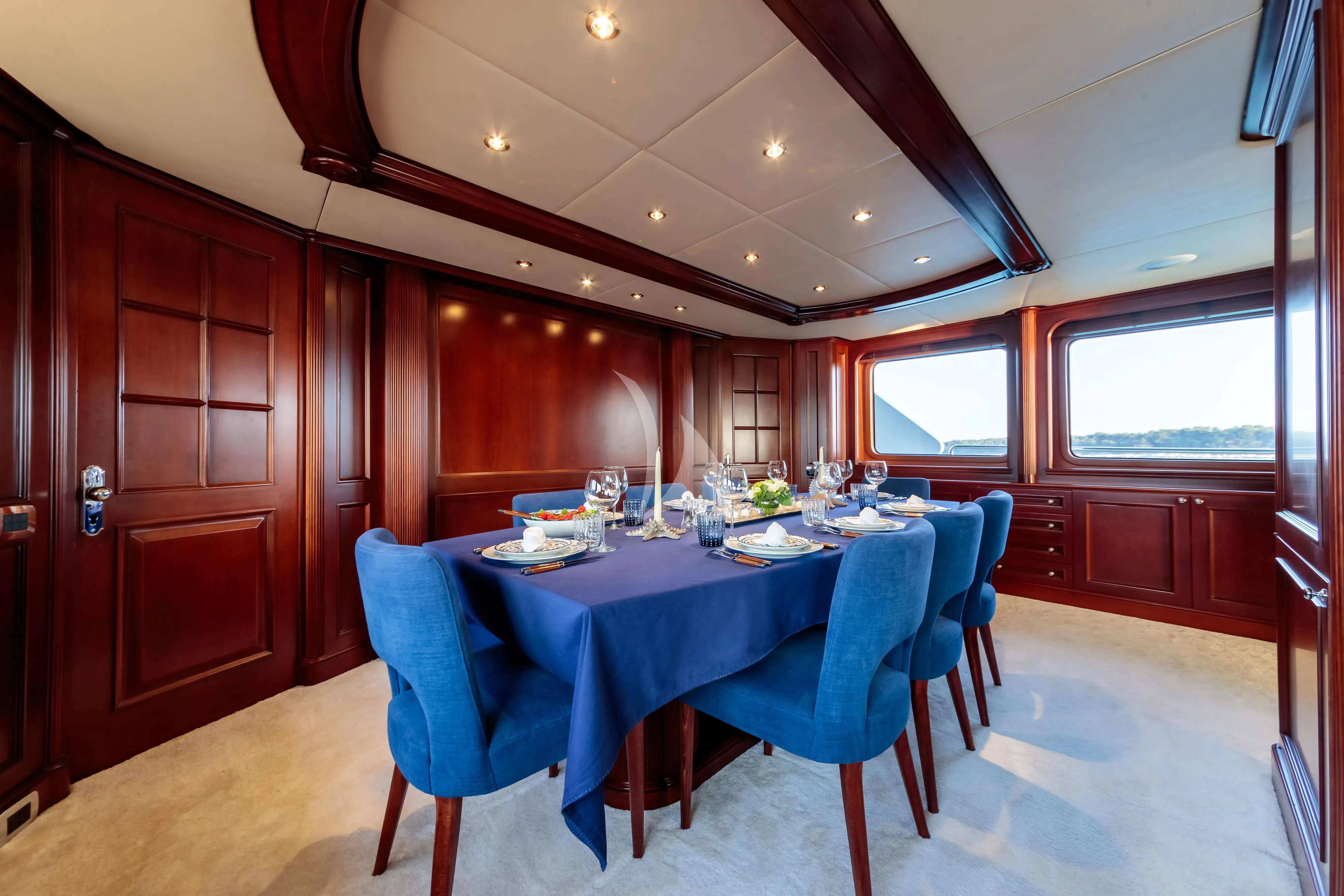 a dining room with a blue table aboard BANG! Yacht for Charter