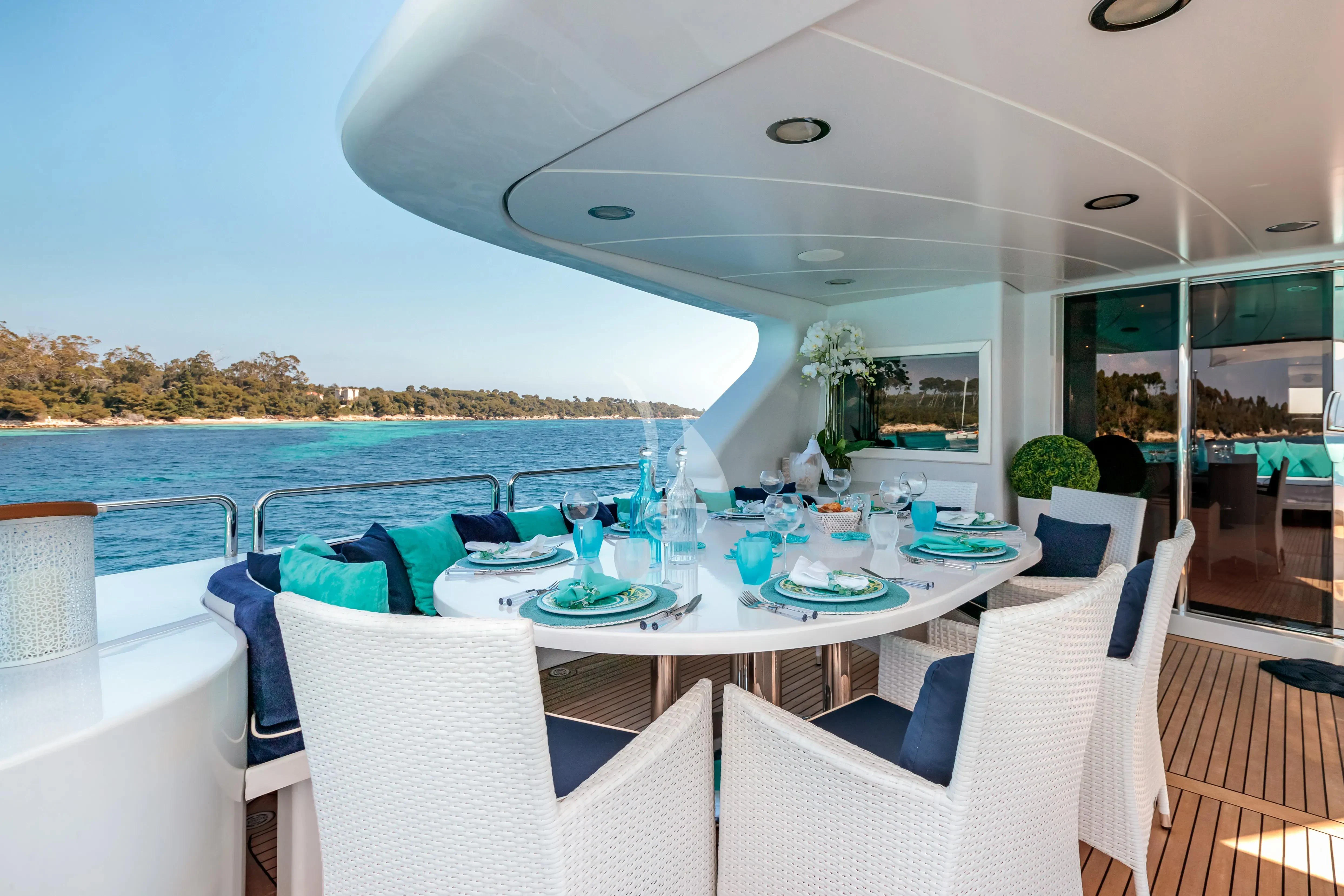 a table set for a meal on a deck overlooking the ocean aboard BANG! Yacht for Charter