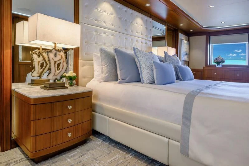 a bed with a white comforter and a lamp on top aboard MAISON BLANCHE Yacht for Charter