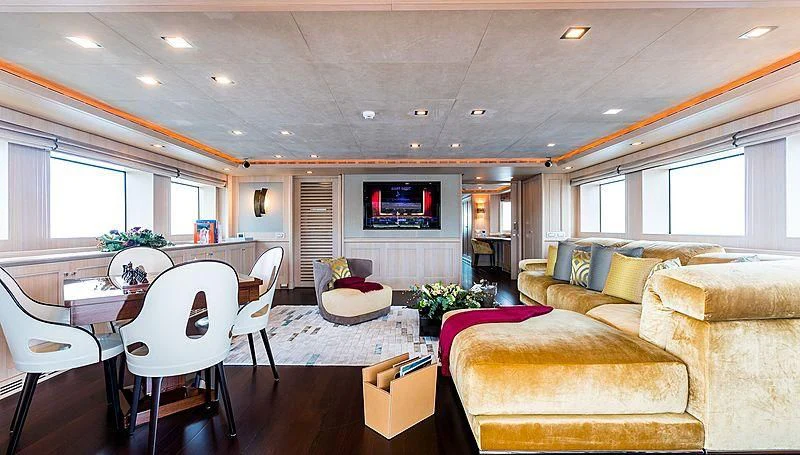 a living room with a table and couches aboard PHOTON Yacht for Sale