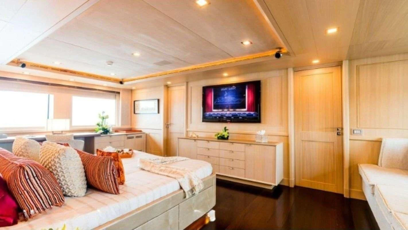 a bedroom with a bed and a tv on the wall aboard PHOTON Yacht for Sale