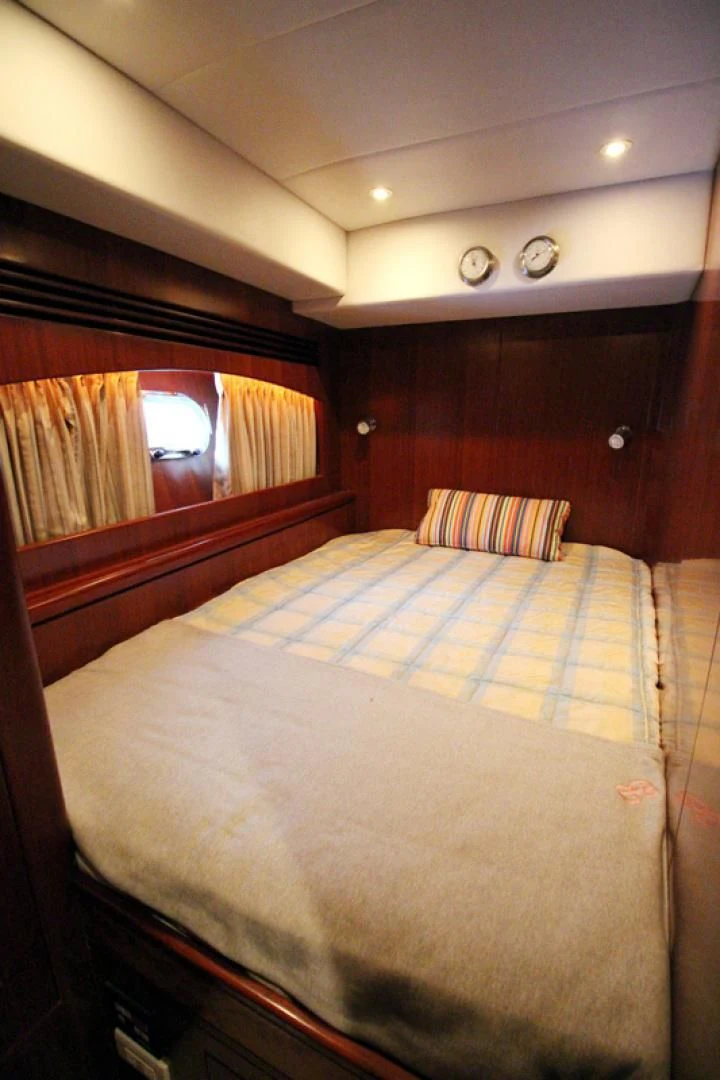 a bed with a blue and white comforter and a window aboard ALWAYS SOMETHING Yacht for Sale