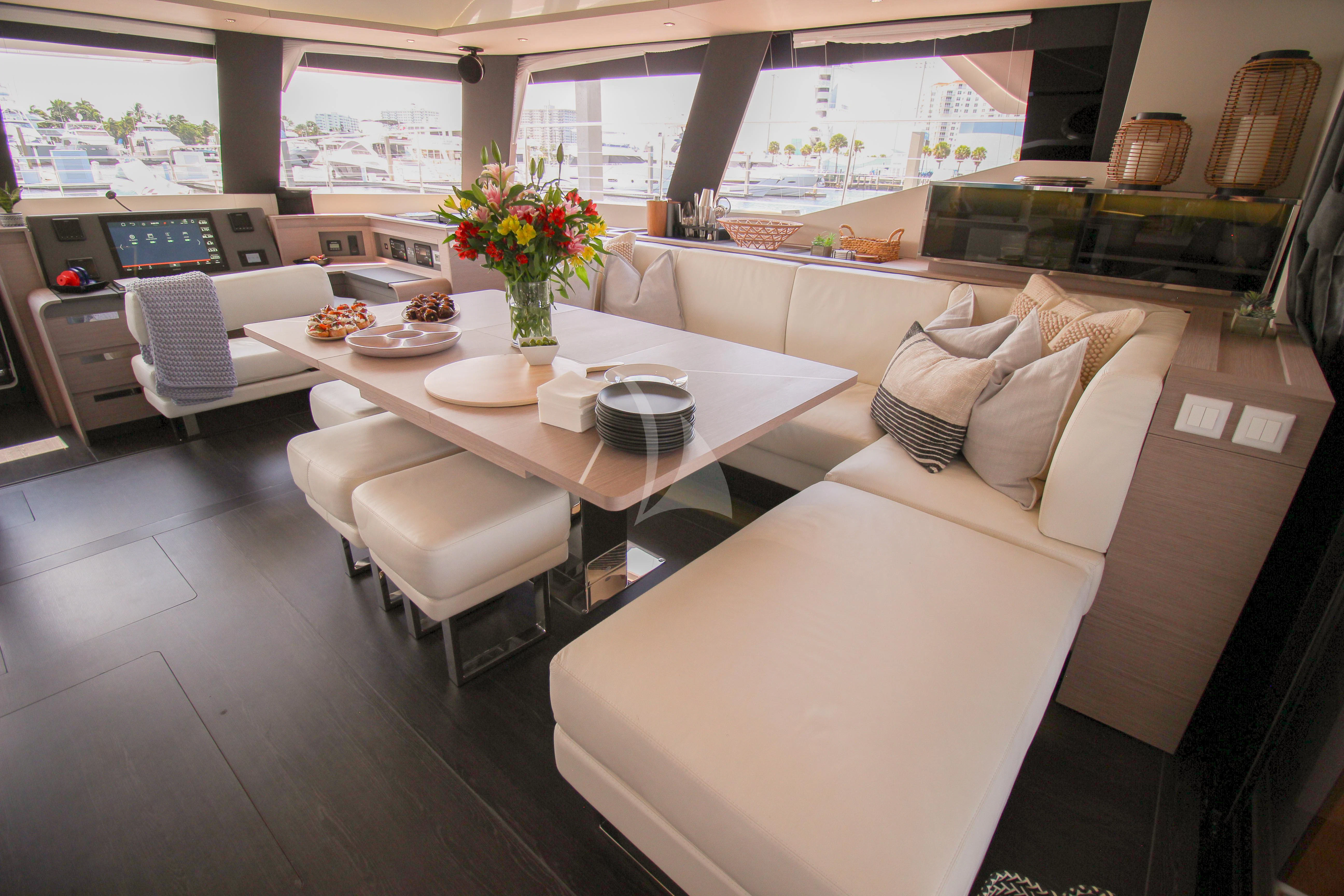 a room with a couch and a table with chairs and a vase with flowers on it aboard PRINCESS MILA Yacht for Charter