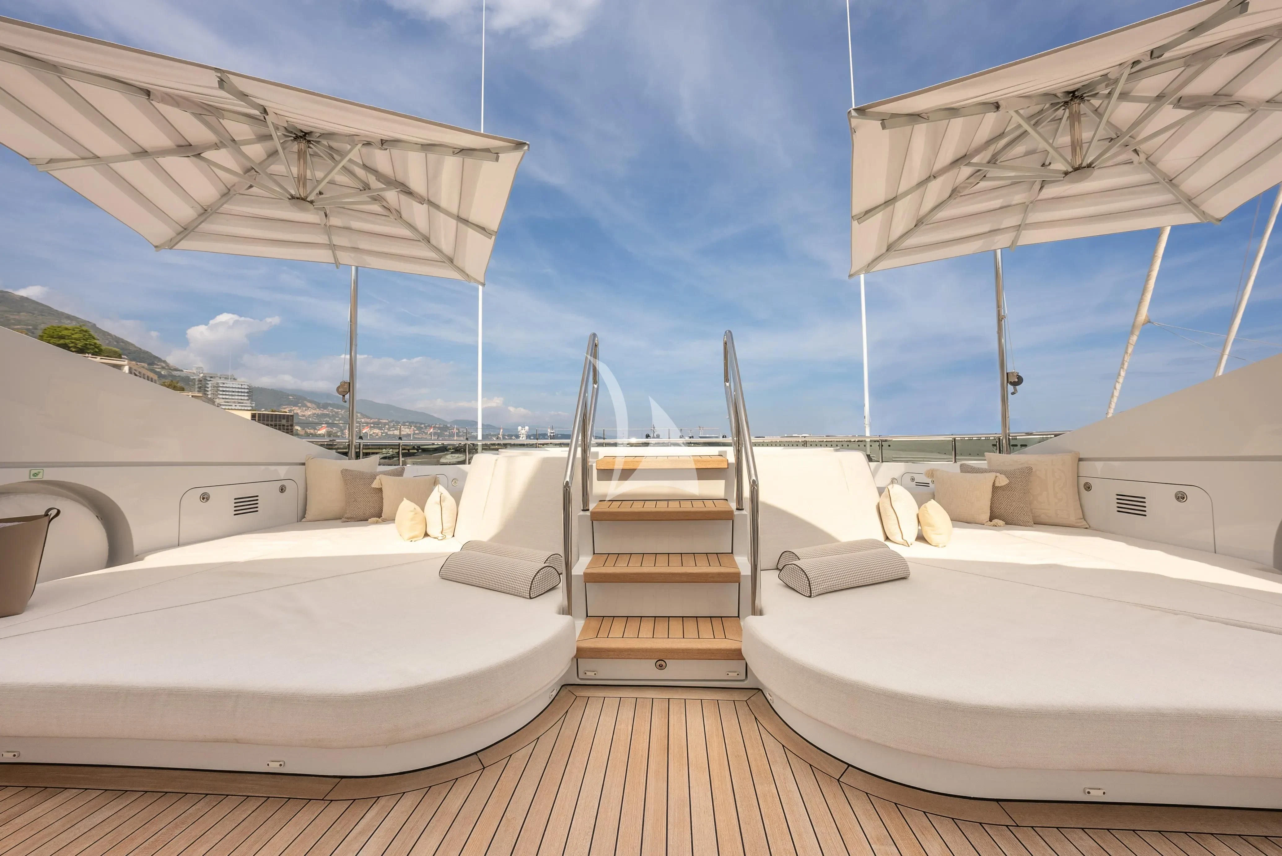 a group of white beds in a room with a wood floor and a white roof with Getty Center in the background aboard RELIANCE Yacht for Sale
