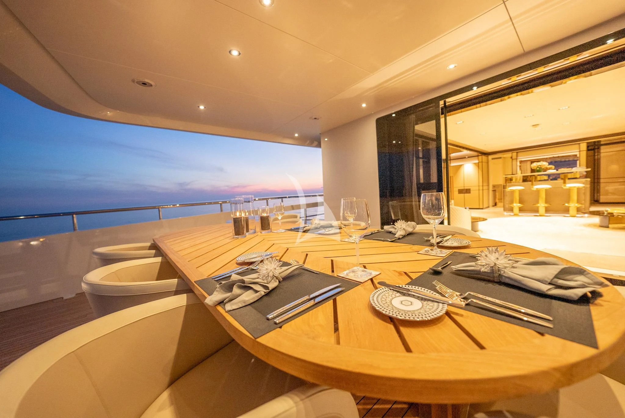 a table with a glass of wine and a view of the ocean aboard RELIANCE Yacht for Sale