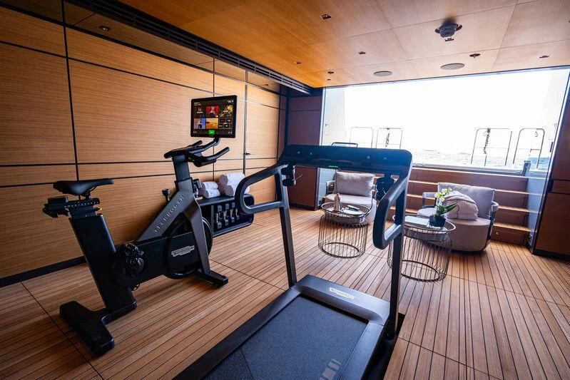 a room with a large window and a table with chairs and a television aboard RELIANCE Yacht for Sale
