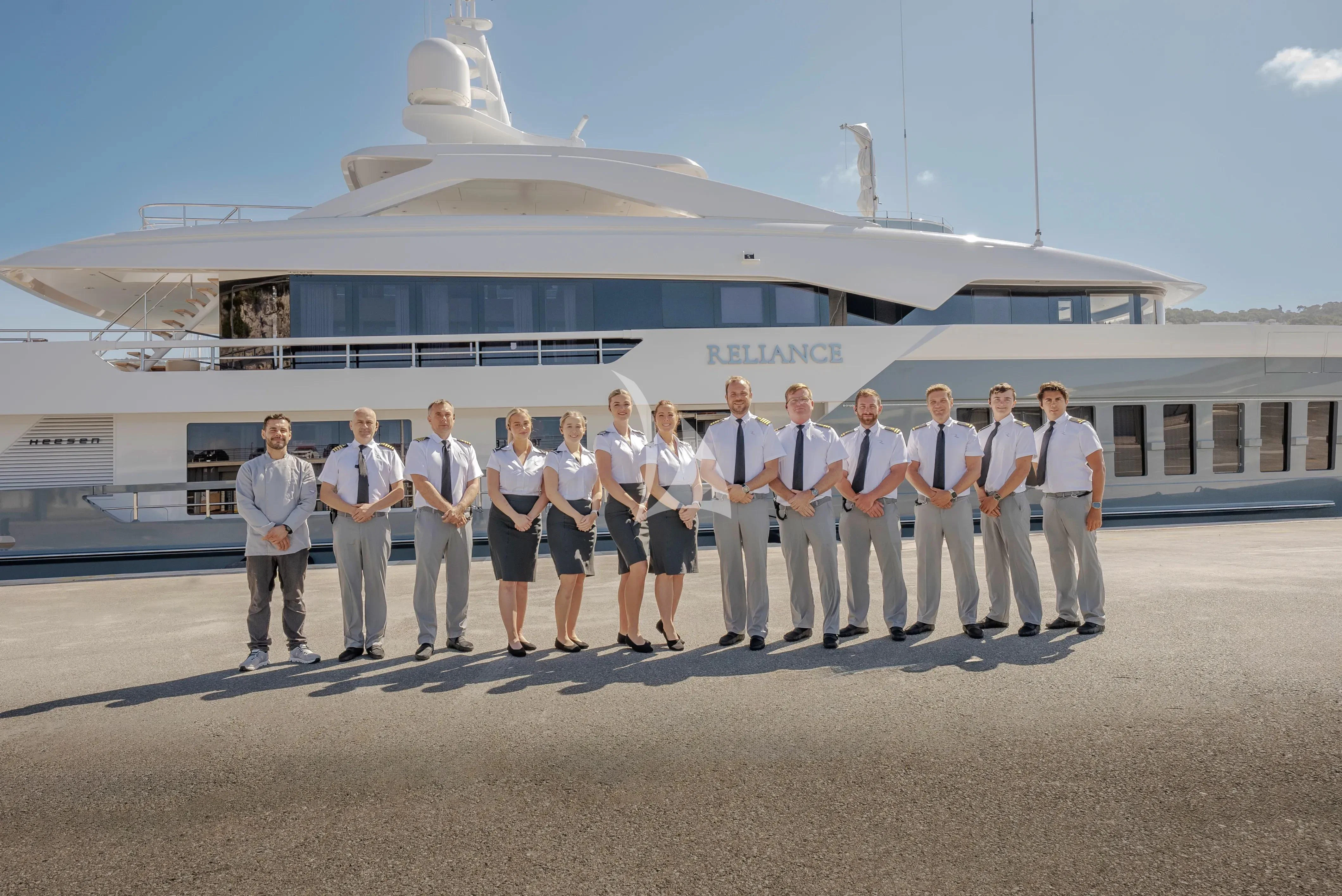 a group of people posing for a photo in front of a large white building aboard RELIANCE Yacht for Sale