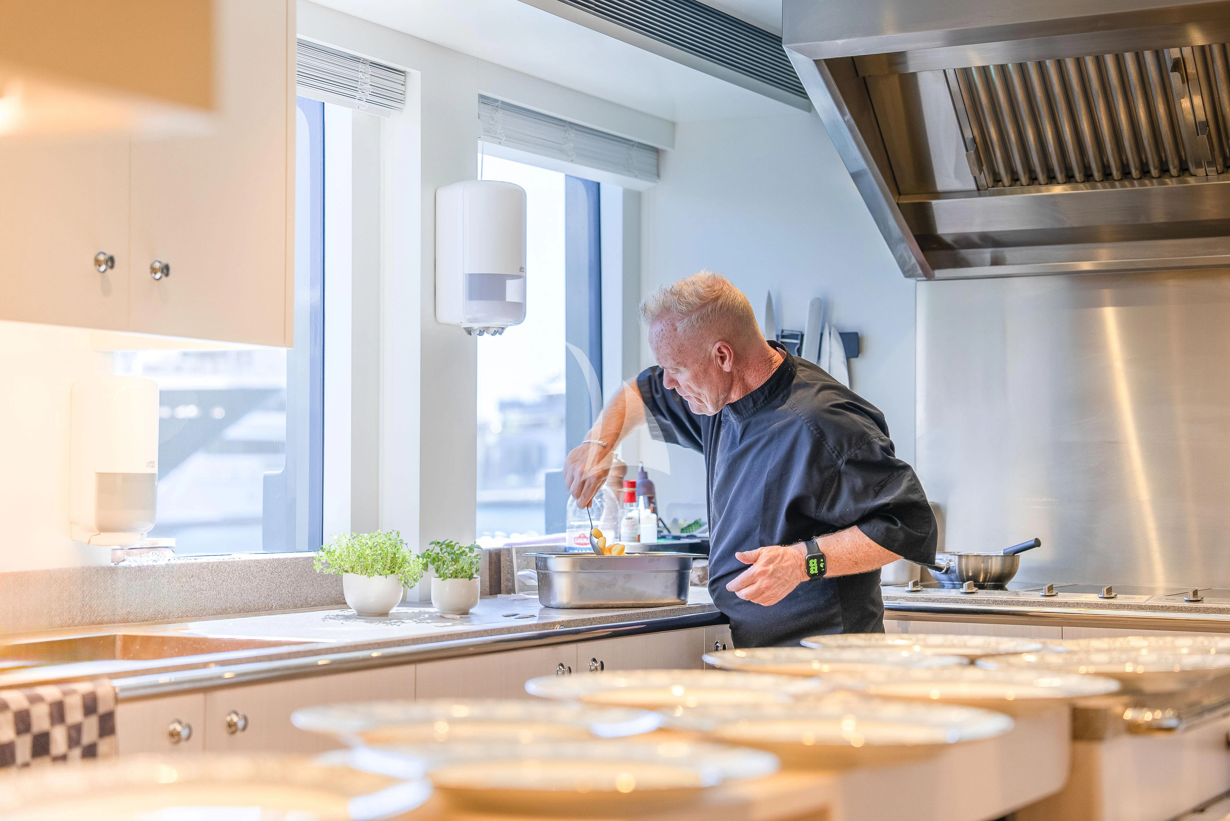 a person cooking in a kitchen aboard RELIANCE Yacht for Sale