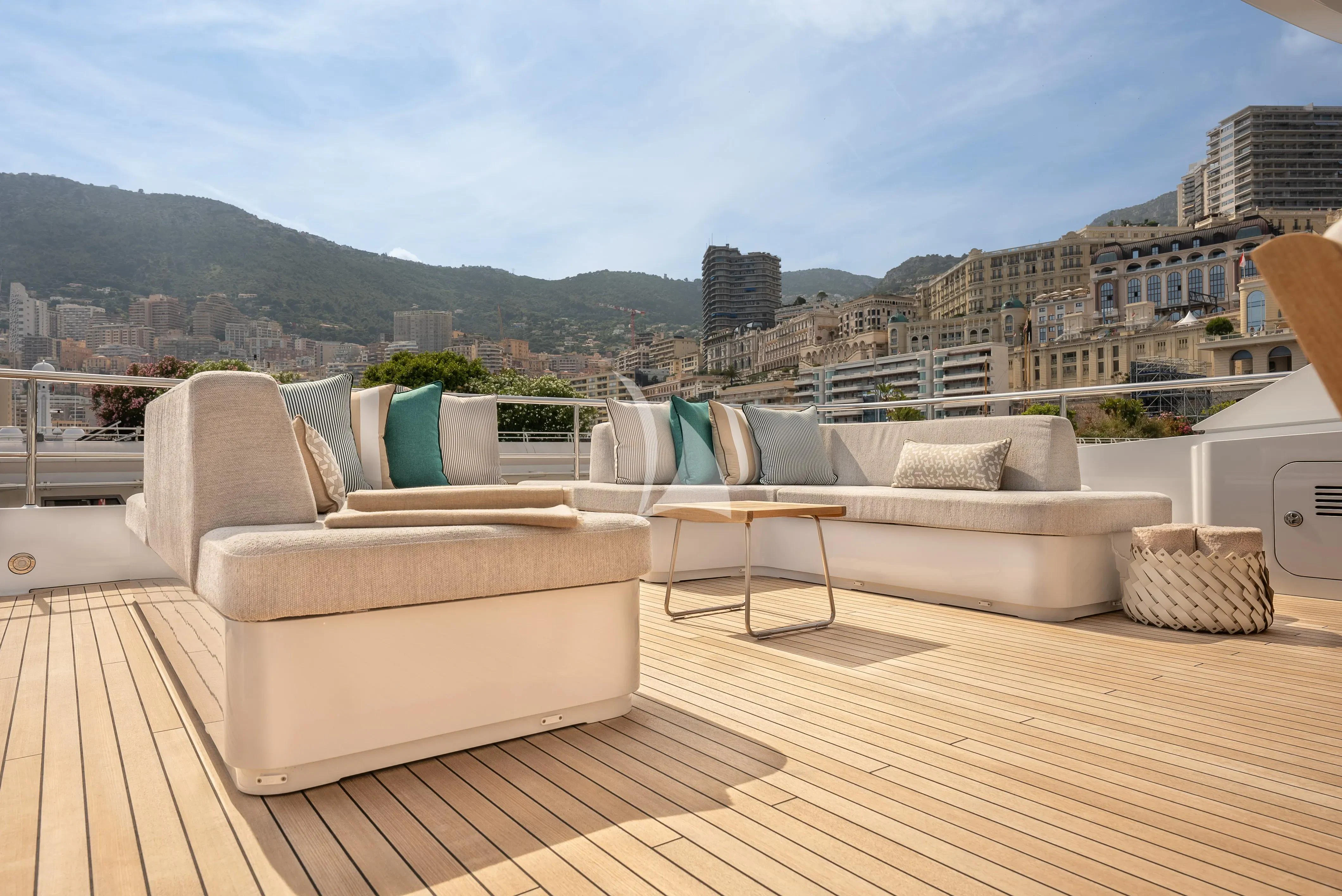 a patio with couches and a table and a city in the background aboard RELIANCE Yacht for Sale