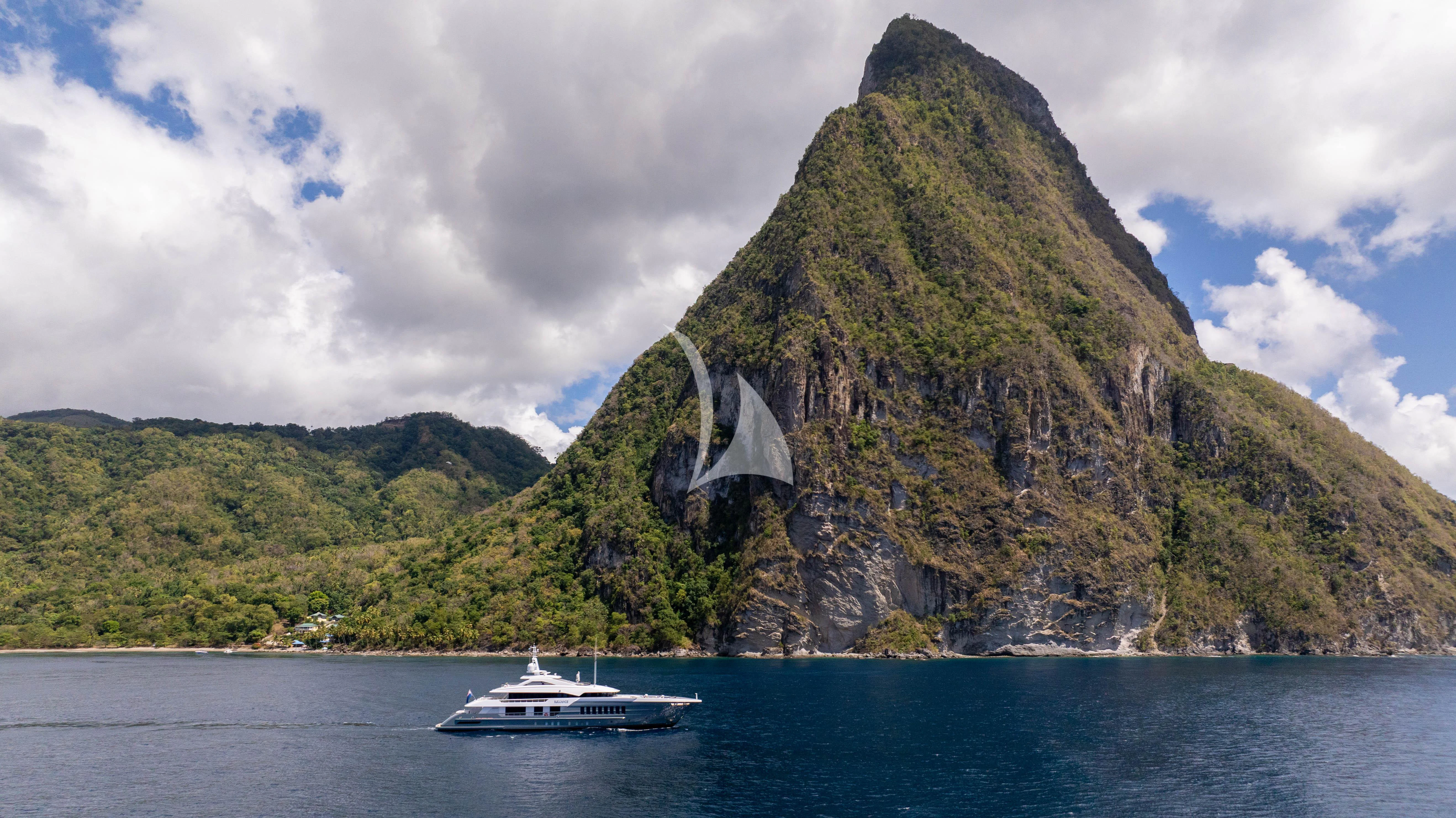 a boat on the water with Pitons in the background aboard RELIANCE Yacht for Sale