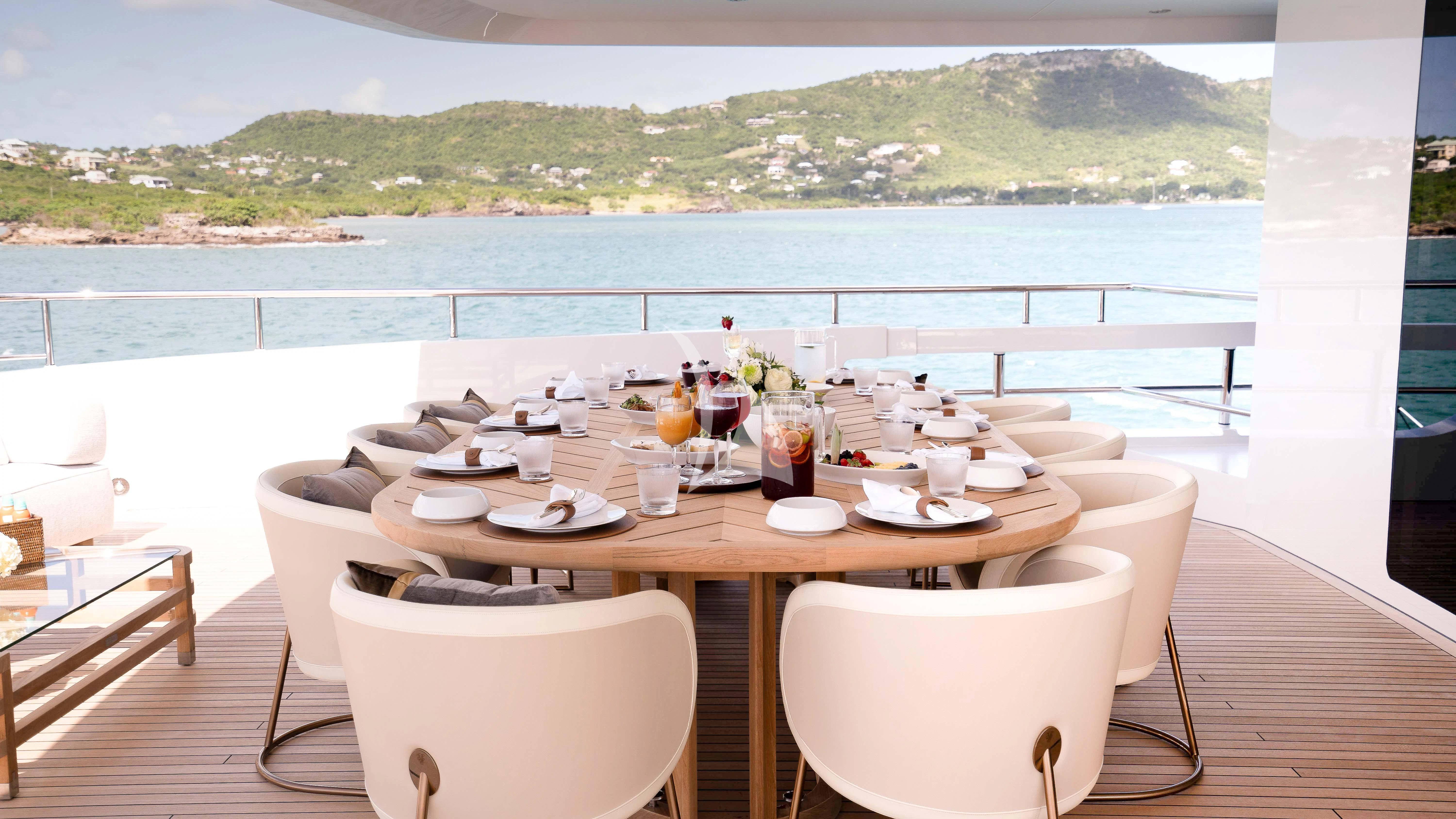 a table set for a meal on a balcony overlooking a body of water aboard RELIANCE Yacht for Sale