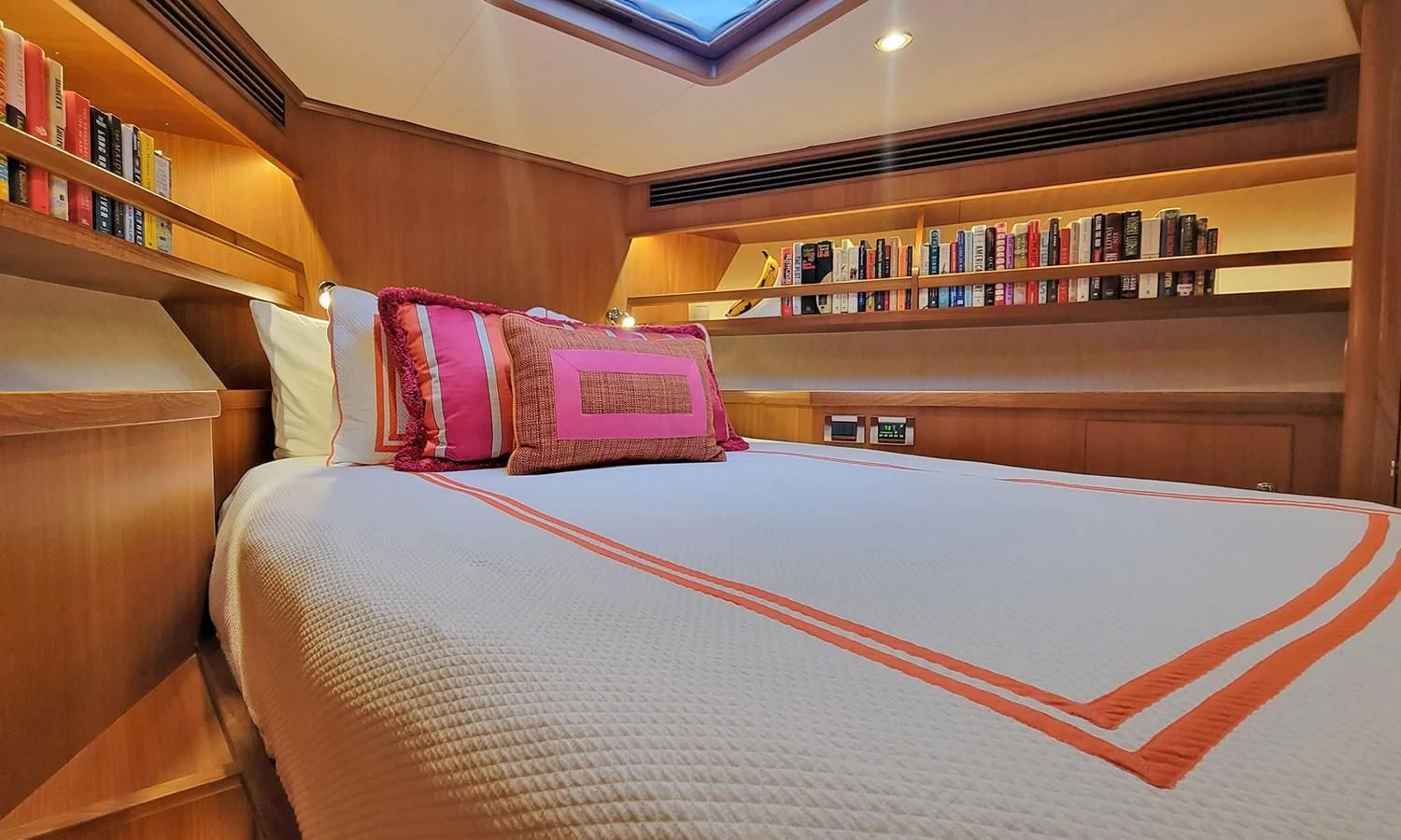 a bed with a pink and white comforter in a room with shelves aboard SUERTUDO Yacht for Sale