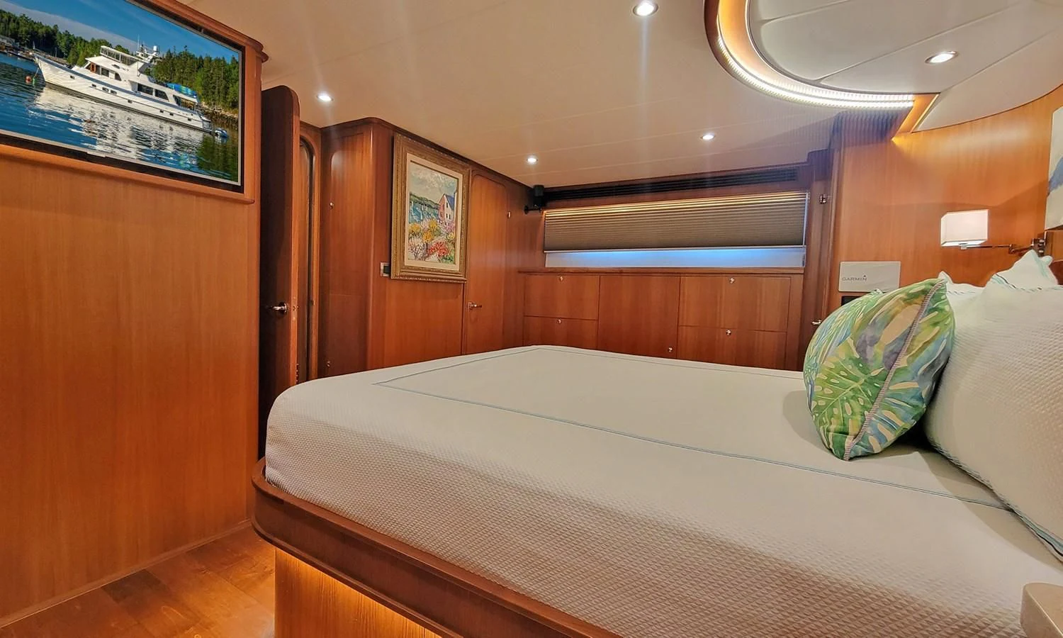 a bed with pillows and a painting on the wall aboard SUERTUDO Yacht for Sale