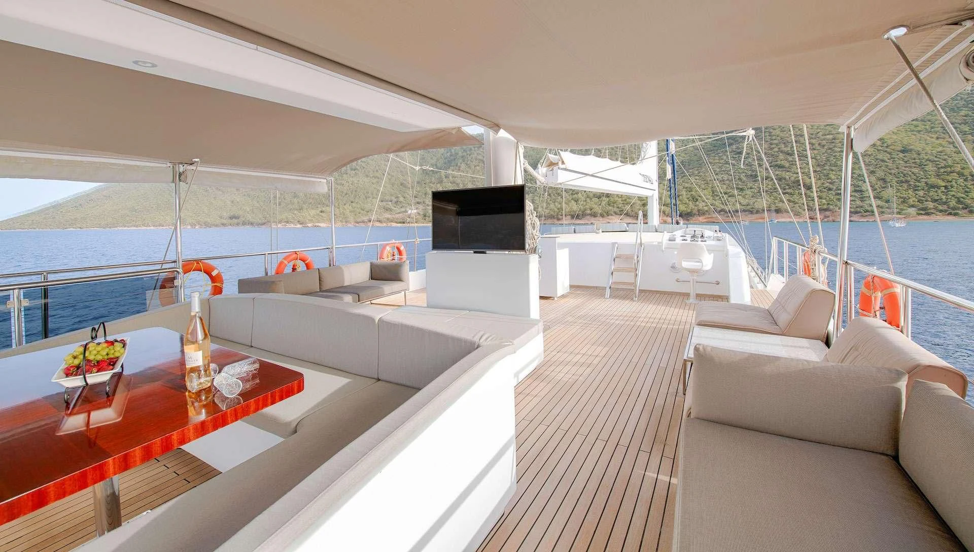 a room with a large screen and a table with chairs and a television aboard THE WALL Yacht for Sale