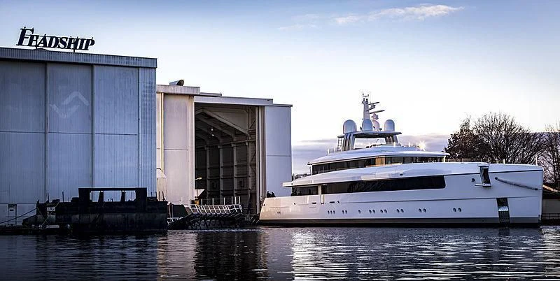 a large white boat sits in front of a building aboard JC Yacht for Sale