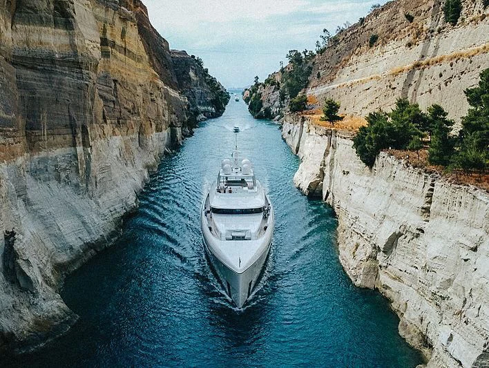 a boat in a river with Corinth Canal in the background aboard JC Yacht for Sale