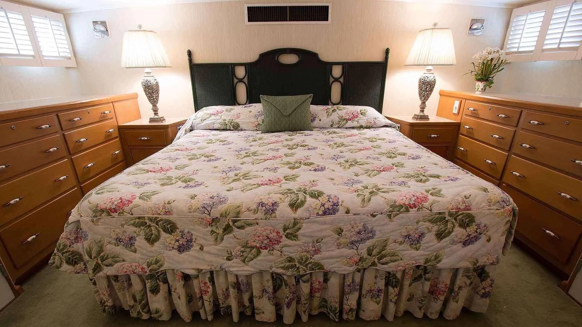 a bed with a flowered comforter and a dresser with a lamp on it aboard KOALA Yacht for Sale