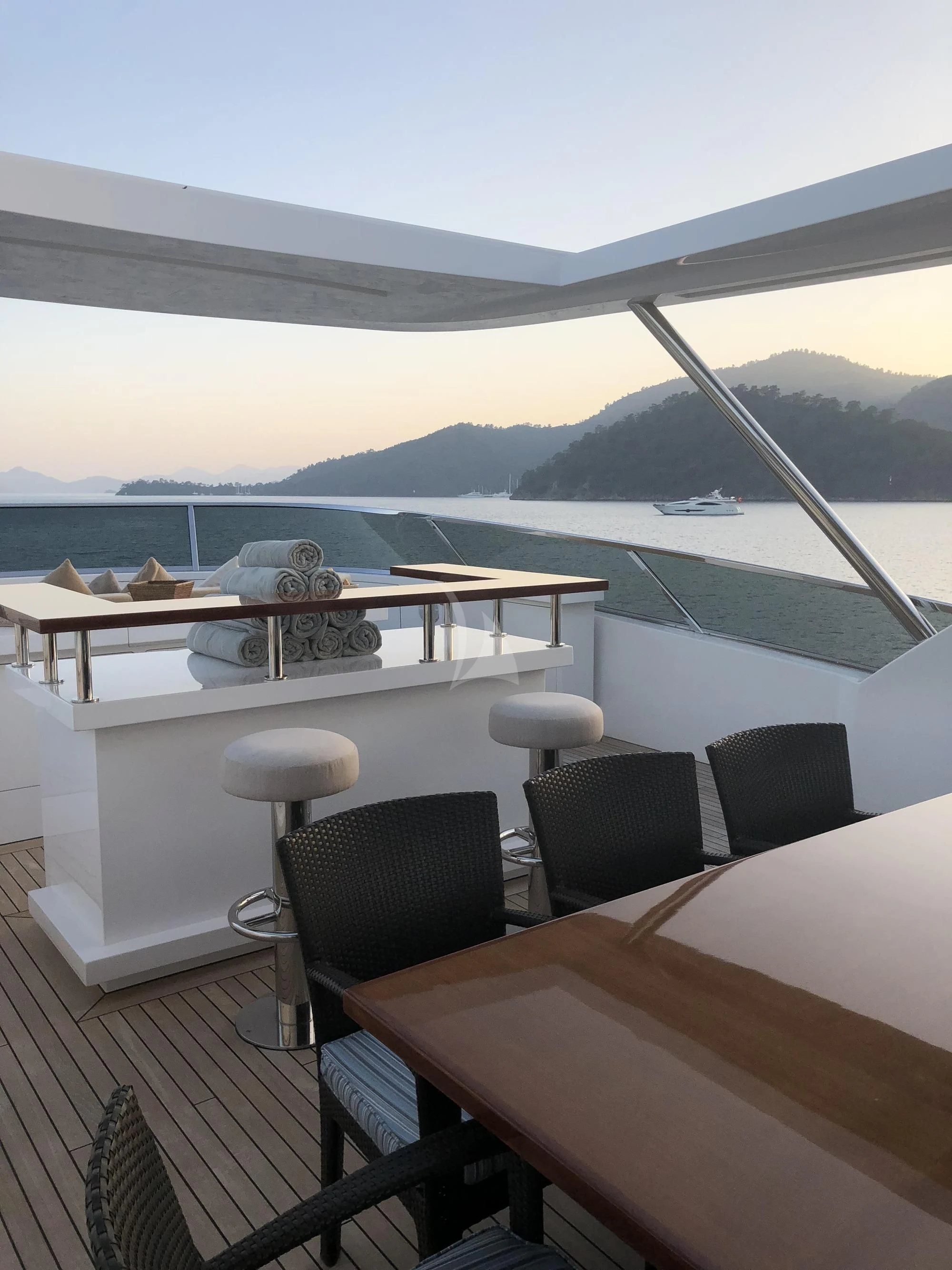 a table and chairs on a deck overlooking a body of water aboard ORYX Yacht for Sale