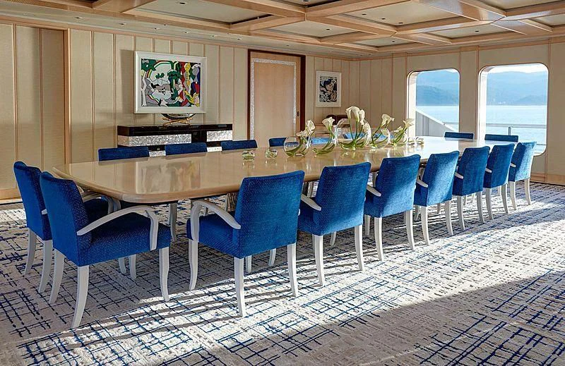 a room with blue chairs and a screen on the wall aboard AQUARIUS Yacht for Sale