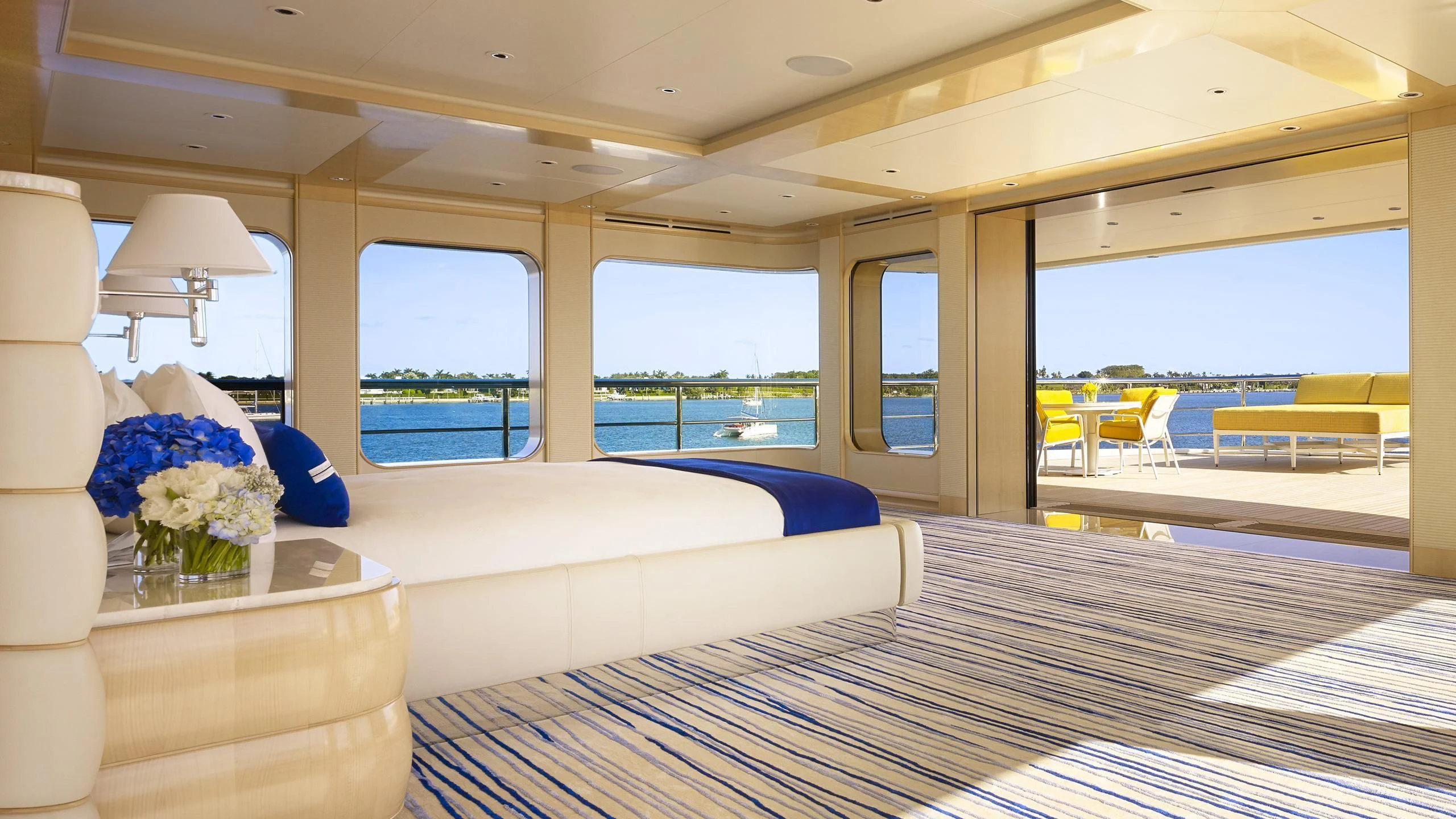 a room with a bed and a table and a large window aboard AQUARIUS Yacht for Sale