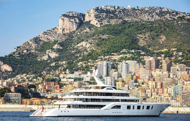a cruise ship in front of a city on a mountain aboard AQUARIUS Yacht for Sale