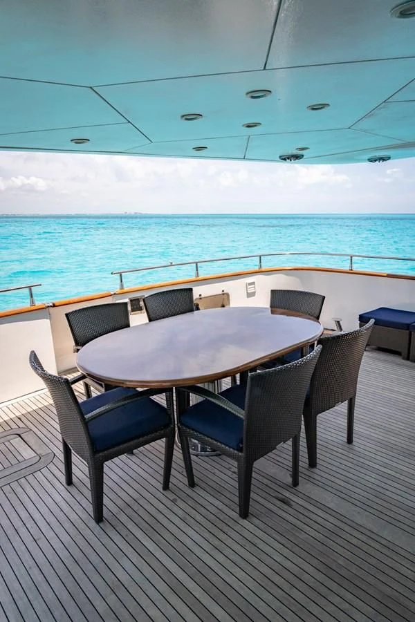 a table and chairs on a deck overlooking a body of water aboard EL CAPRICHO Yacht for Sale