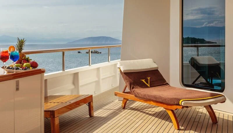 a bed and a table on a balcony overlooking a body of water aboard VERA Yacht for Sale