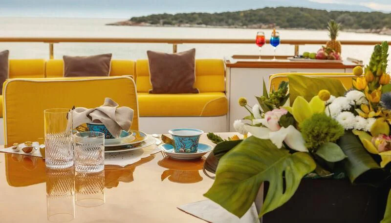 a table with a plate of food and glasses on it aboard VERA Yacht for Sale