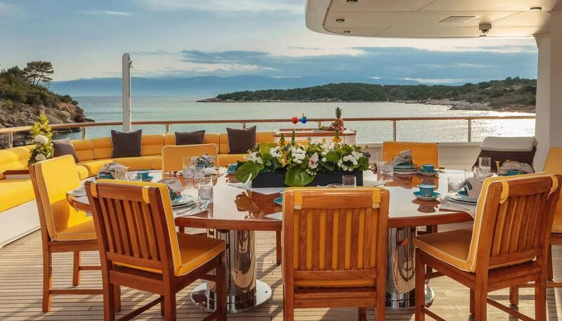 a table with chairs and a view of the ocean aboard VERA Yacht for Sale