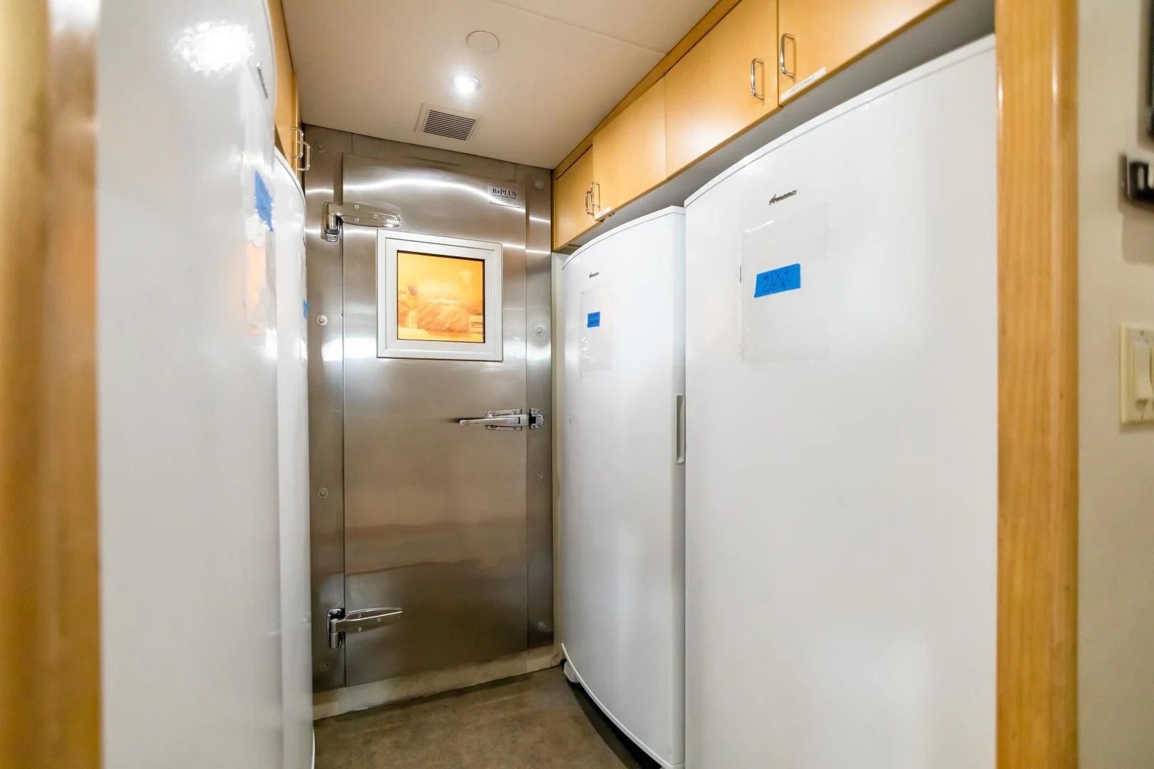 a room with a refrigerator and a door aboard AMORE Yacht for Charter