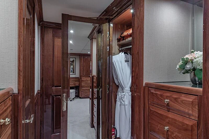 a person in a white robe in a room with wood cabinets aboard AMORE Yacht for Charter