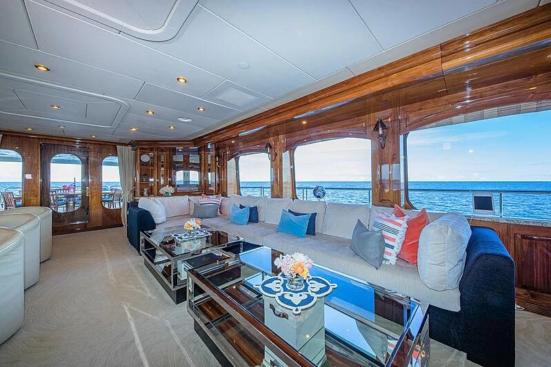 a large living room with a large blue couch and a large window aboard AMORE Yacht for Charter