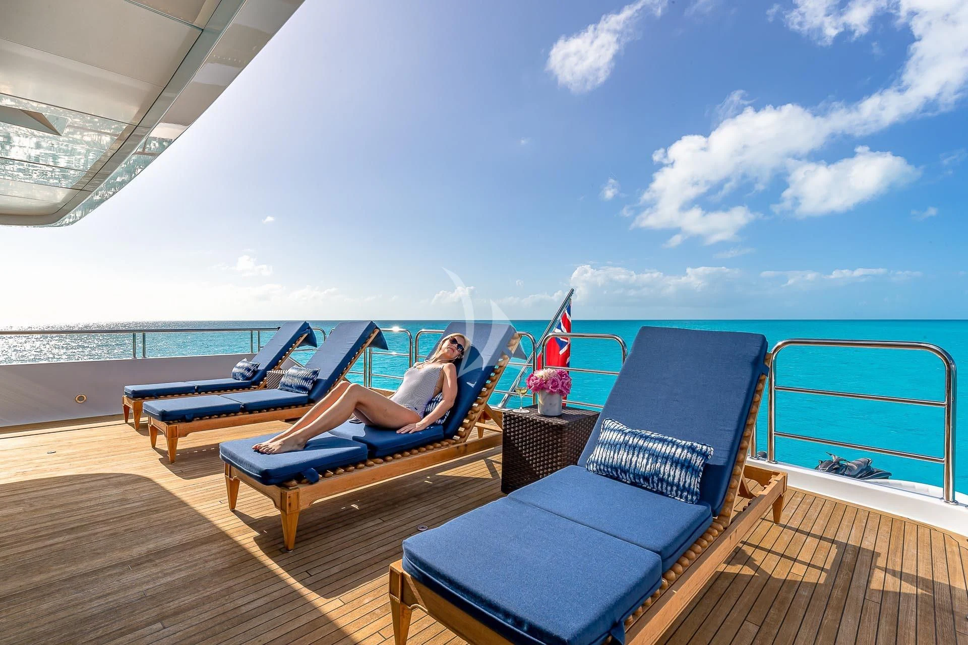 a person lying on a lounge chair on a deck overlooking the ocean aboard AMORE Yacht for Charter