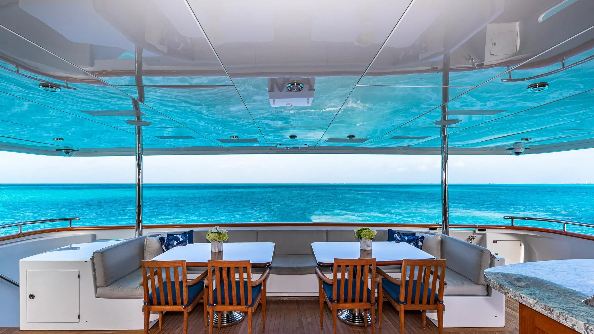 a room with a table and chairs and a large body of water aboard AMORE Yacht for Charter