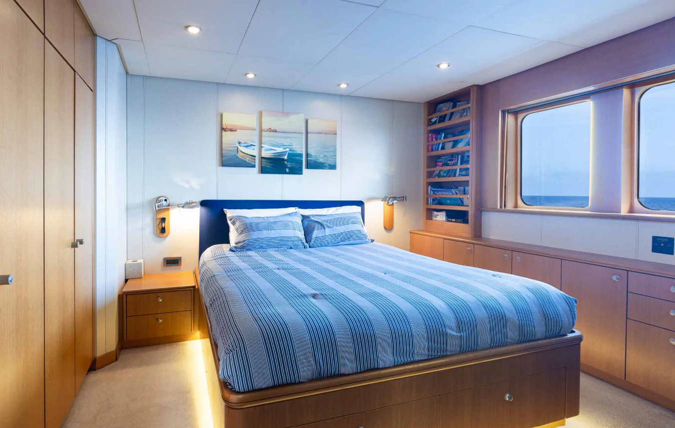 a bedroom with a bed and a bookcase aboard VIBRANCE Yacht for Sale