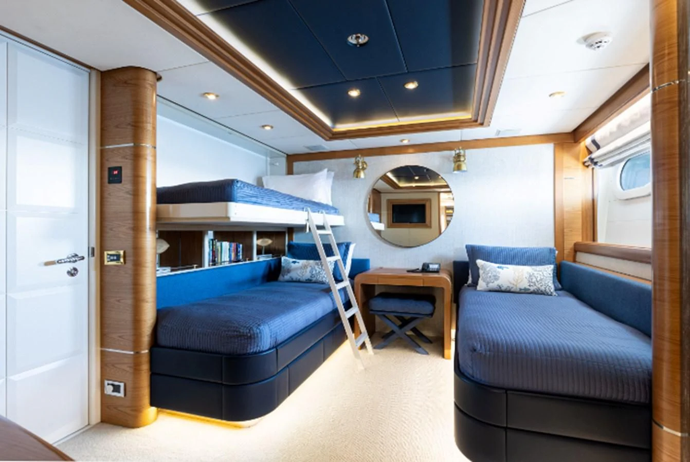 a bedroom with a blue couch and a mirror aboard VIBRANCE Yacht for Sale